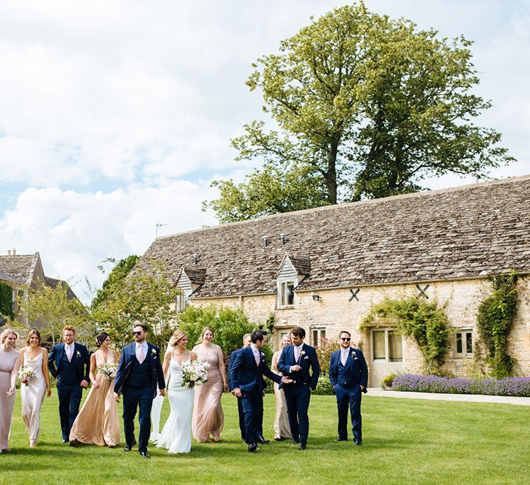 Wedding party portrait at summer Caswell House wedding with groomsmen in navy suits and bridesmaids in different shades of pink dresses 