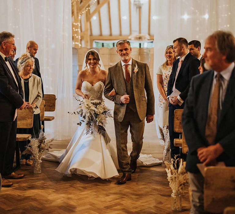 Bride walks down the aisle in strapless wedding dress with pampas grass bouquet