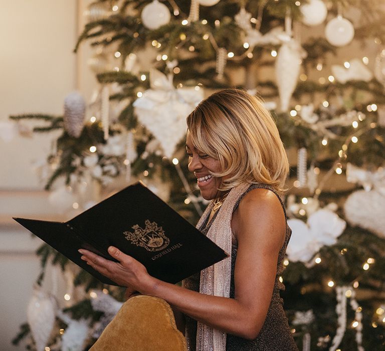 Celebrant reads during wedding ceremony whilst stood in front of Christmas tree 