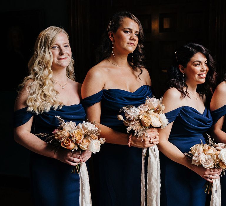 Bridesmaids in 1930s style navy blue bridesmaid dresses and neutral bouquets with side swept curled hair