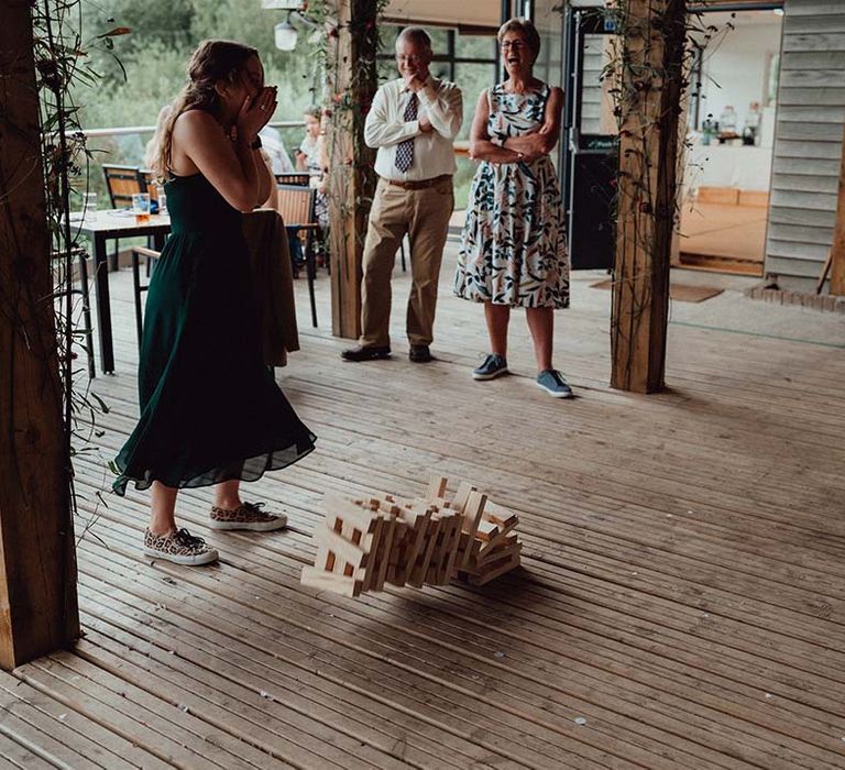 Wedding guests laugh as they play jenga on the deck of the cabin at lake wedding venue 