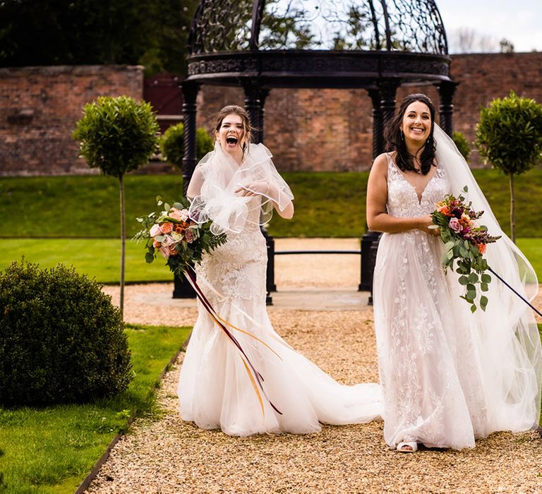 Brides walk their pet dog in colourful bow tie collar who was ring bearer during the ceremony