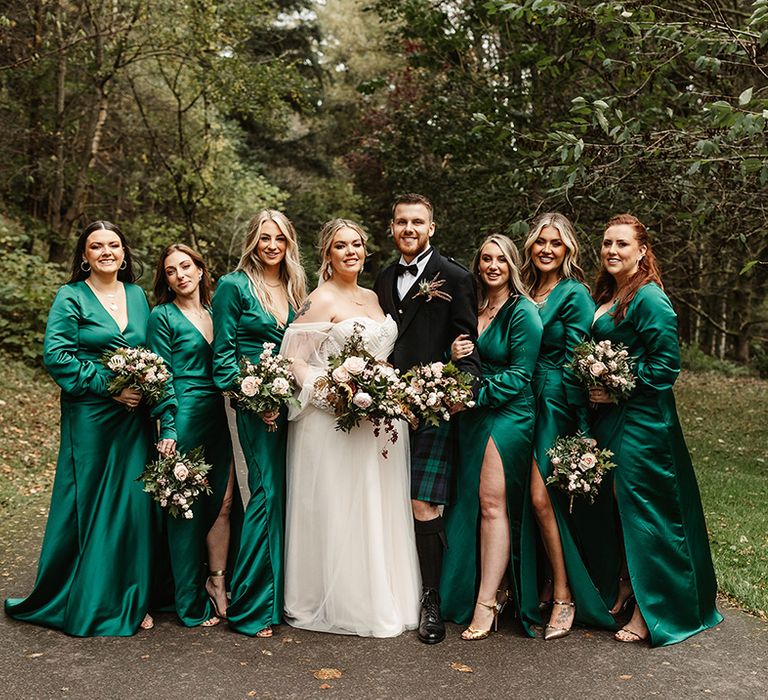 Bridal party with bridesmaids in emerald green v-neck long sleeve front slit dresses with bride and bridesman 