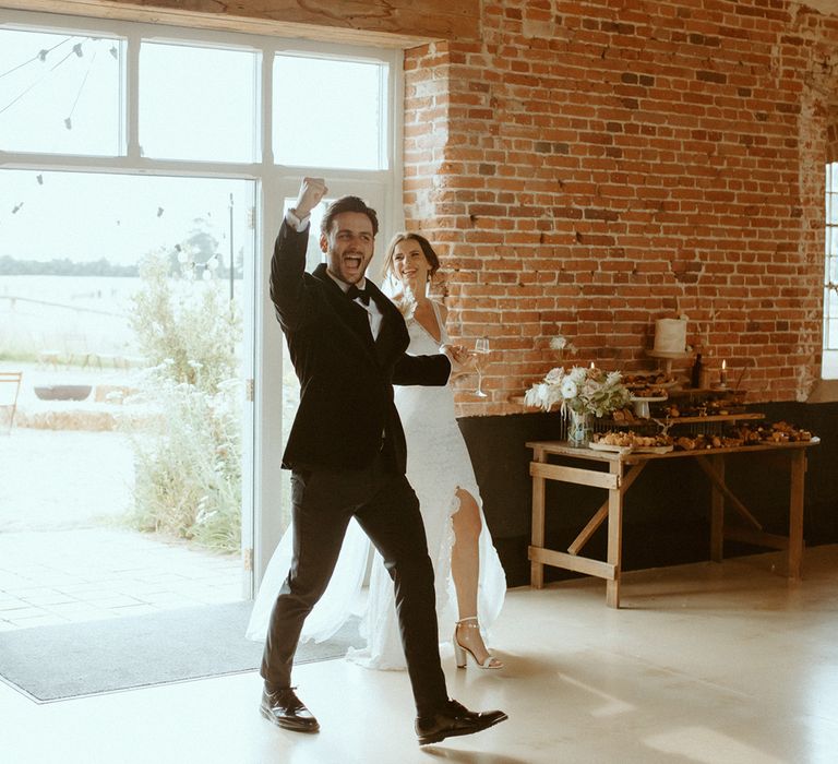 Groom fist pumps as he walks into the wedding reception with the bride