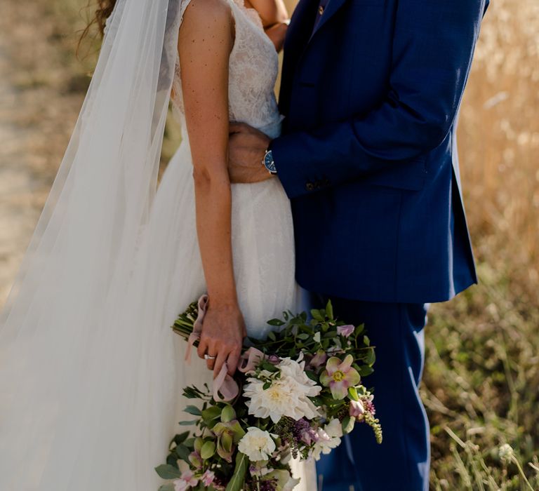 Bride & groom stand in golden fields on their wedding day in Tuscany 