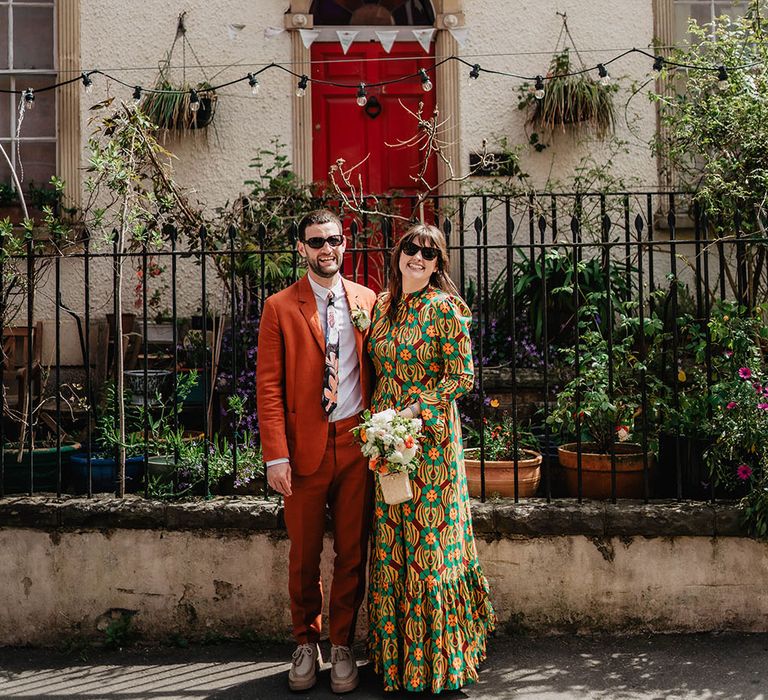 Bride & groom laugh and smile brightly outdoors on their wedding day in Bristol whilst wearing sunglasses 