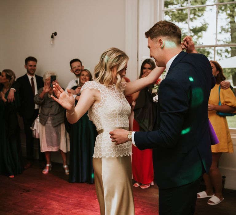 Bride & groom dance as bride wears gold silk wedding gown complete with scalloped lace top complete with gold ribbon tie to middle