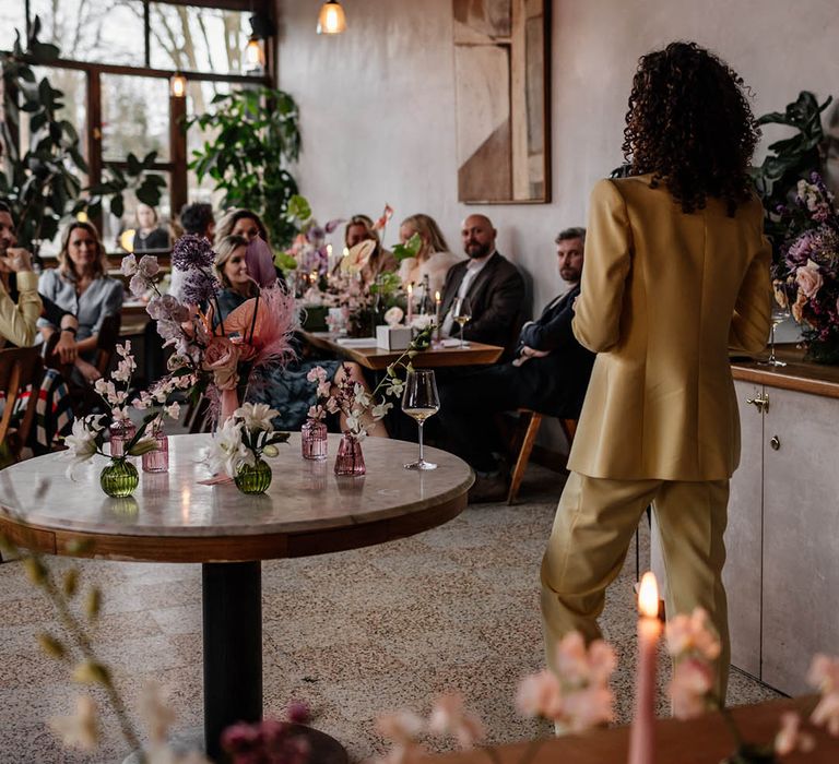 bridesmaid with natural curly hair in a yellow bridesmaid suits giving a wedding speech 