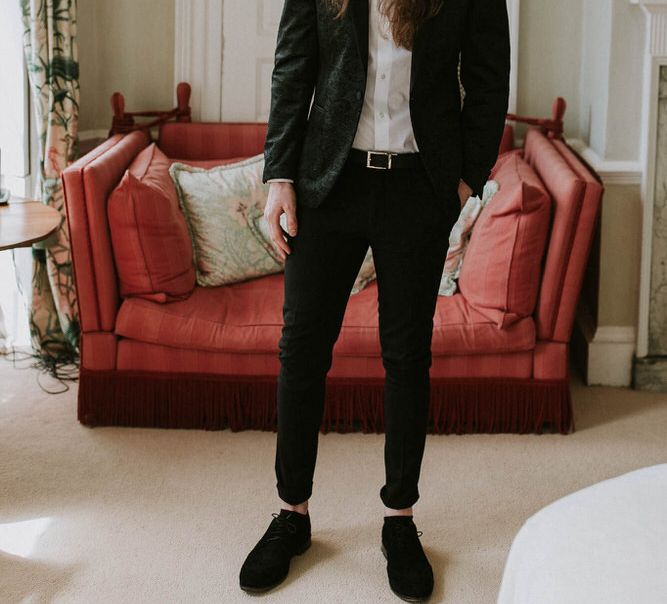 Groom with long hair tied up in a black suit with bow tie 