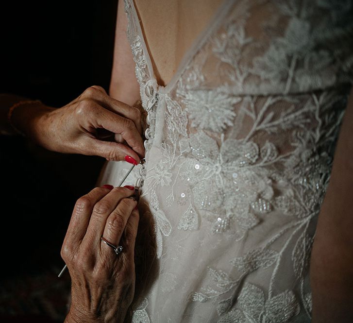 Bride wears lace wedding dress with sequin embellishment and buttoned down back