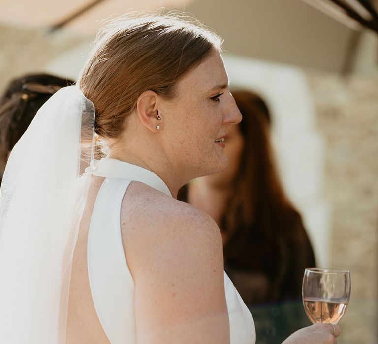 Bride wears her red hair pulled back into low-bun complete with veil and open back London Halfpenny wedding dress