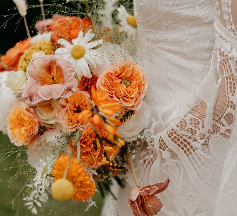 Orange, pink and white wedding bouquet held by bride in lace wedding dress for retro wedding 