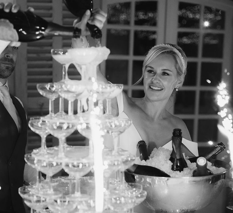 Champagne tower behind sparklers in glasses for outdoor wedding reception 