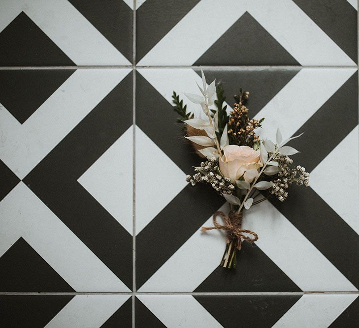 Floral buttonhole with pastel rose tied with brown string 