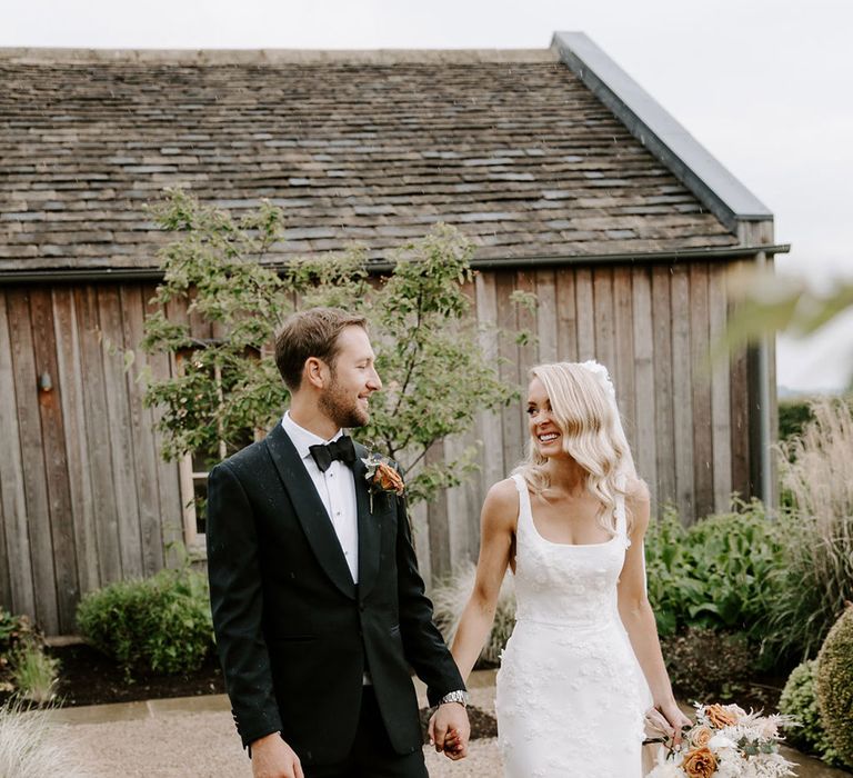 Groom in black tie walks holding hands with the bride in a 3D floral applique wedding dress