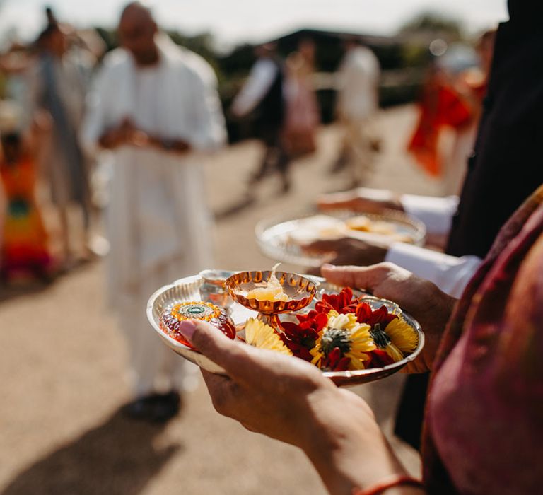 Wedding guest holds out colourful flowers for traditional Indian wedding at High Billinghurst Farm 