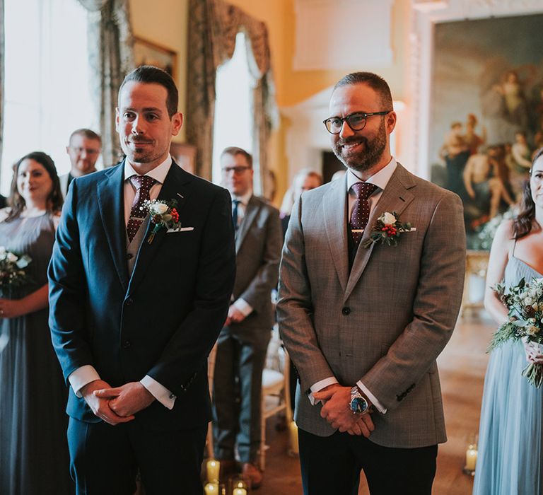 The two grooms stand together at the altar for their wedding ceremony at their country house venue 