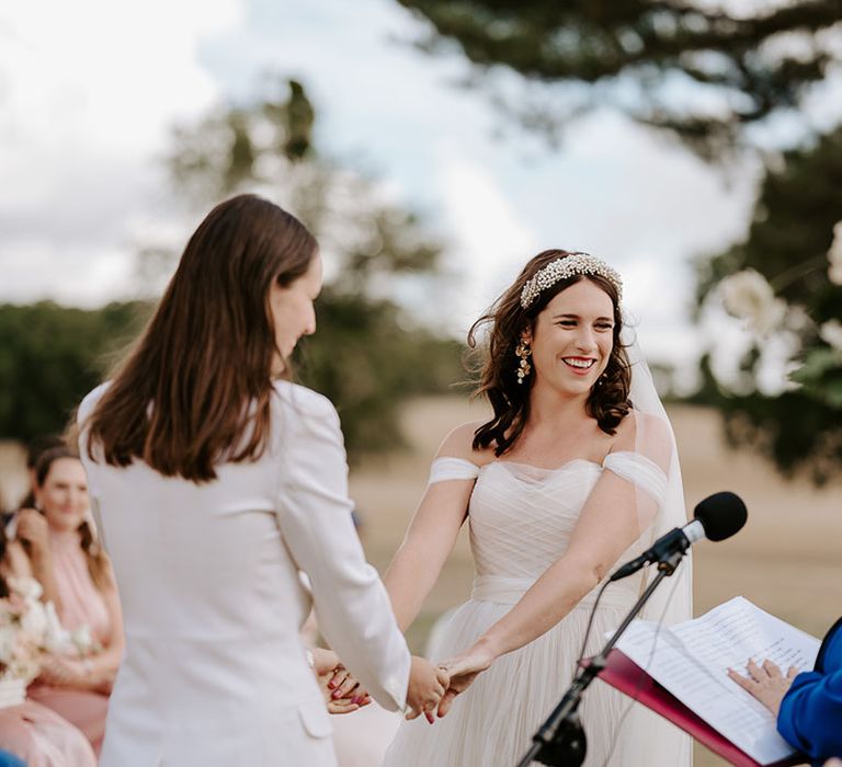 The bride hold both hands together as they participate in their same sex wedding ceremony 