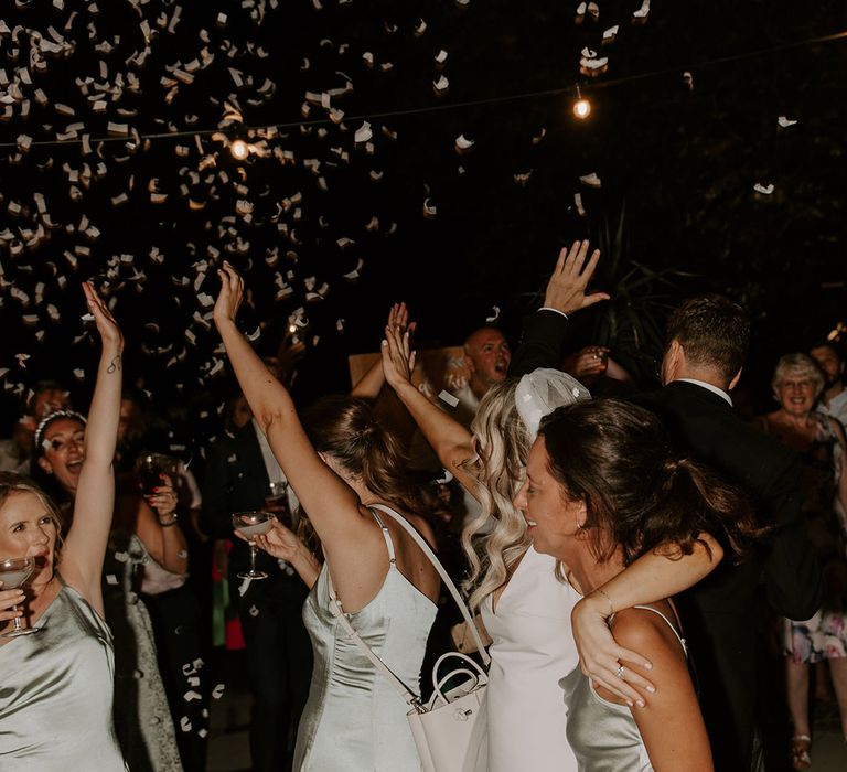 The bride in her Made With Love wedding dress with flower applique veil dances with the bridesmaids in sage green dresses for the reception