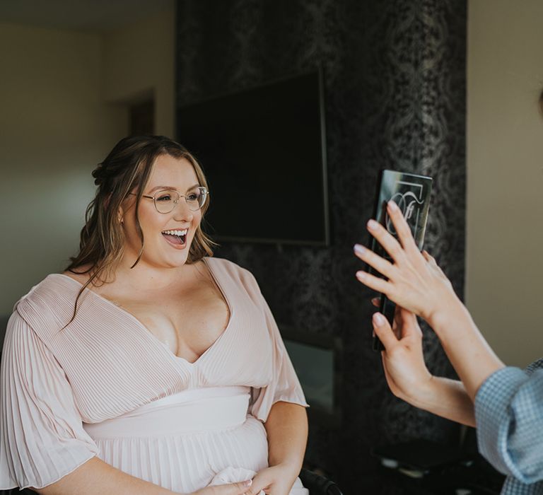 Bridesmaid wears pale pink V-shaped batwing dress 