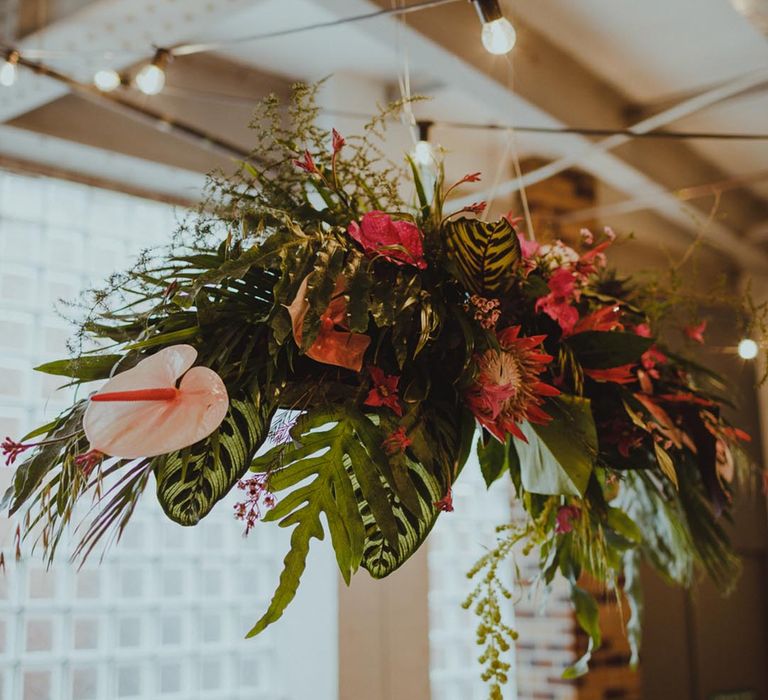 Tropical wedding flower installation with pink anthuriums and palm leaves 