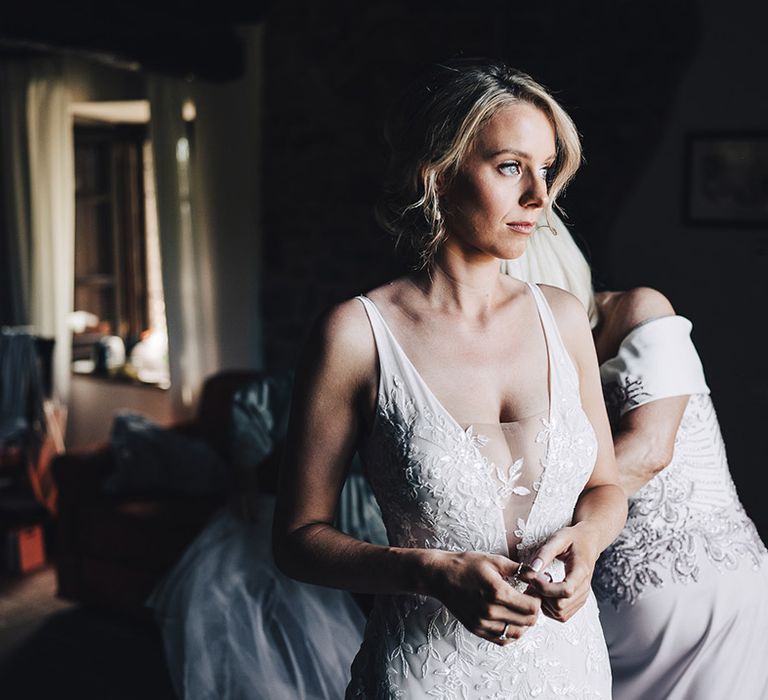 Blonde bride wears plunge neck wedding dress with sheer mesh insert and appliqué lace embellishment 