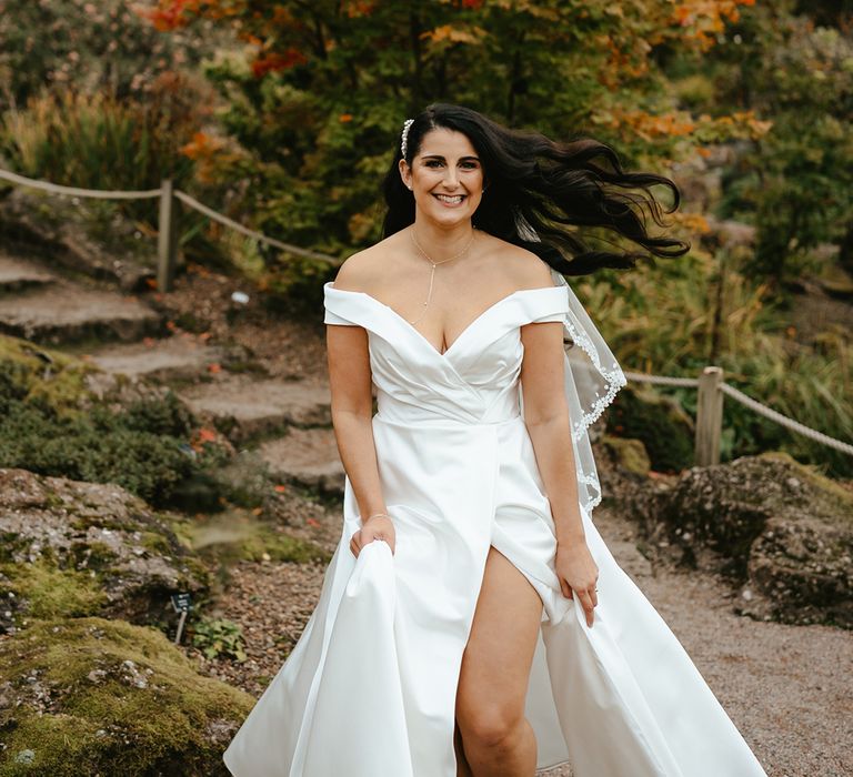 Bride wears satin off-the-shoulder wedding dress with sweetheart neckline and side split to thigh 