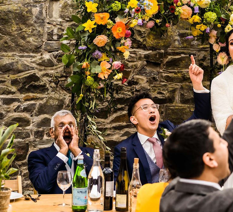 Bride gives speech during reception at Plas Dinam surrounded by colourful florals 