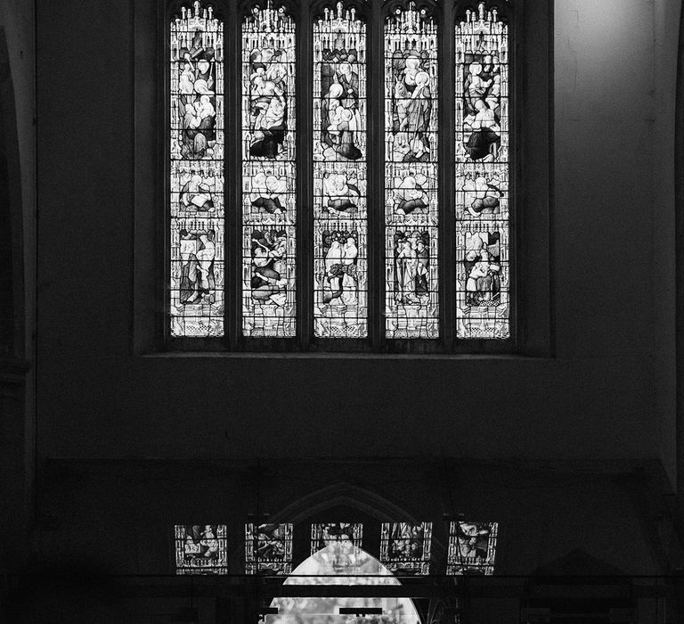 Grand church with stained glass windows with the bride walking down the aisle with the father of the bride for traditional wedding 