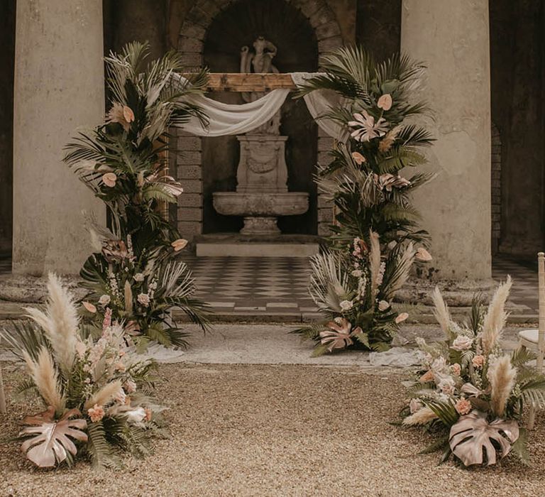 Neutral colour palette for outdoor ceremony with pampas grass, palm leaves, pink flowers and more 