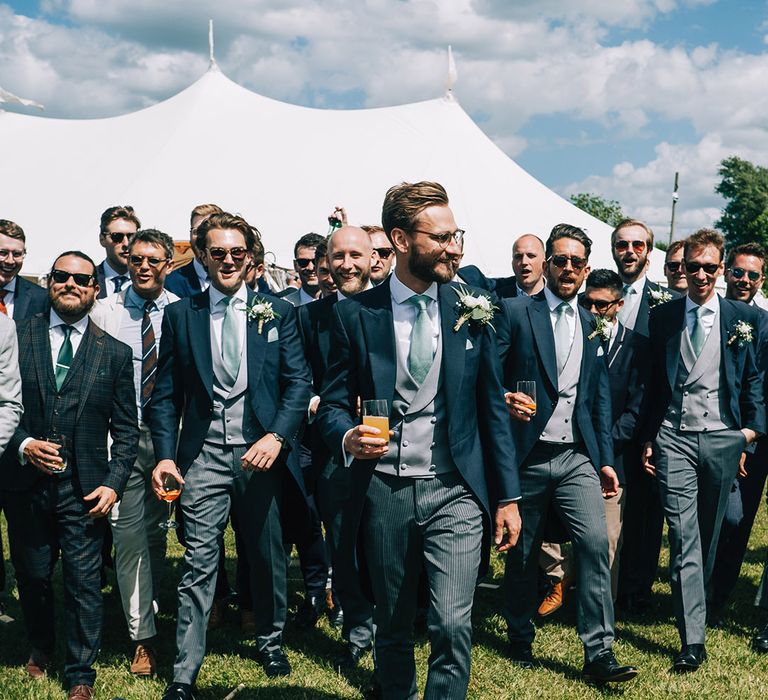 The groom and men in the wedding party all walk together for the fun festival wedding weekend 