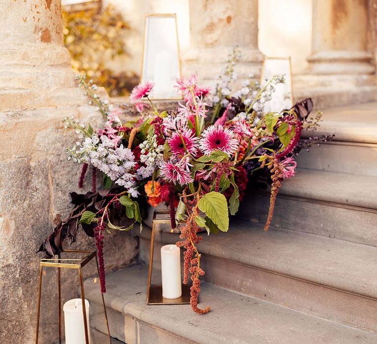 Pink and purple wedding flowers with candle lantern decorations on the stairs at Elmore Court wedding venue 