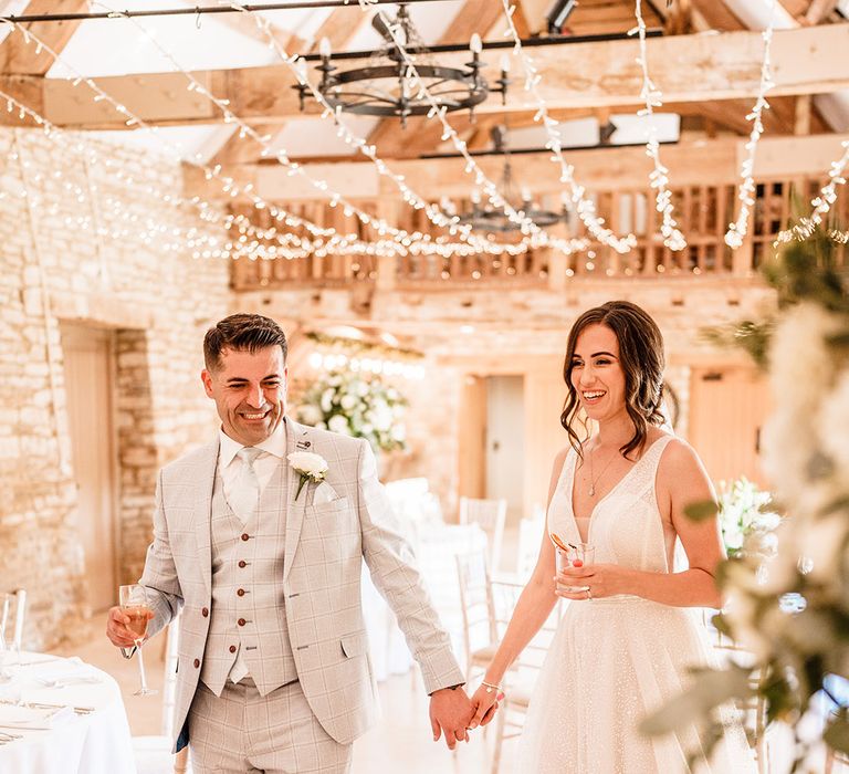 Bride and groom standing in their Caswell House rustic barn wedding reception with fairy lights 