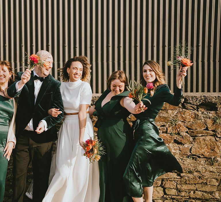 Bride in wedding two piece with the bridesmaids in green bridesmaid dresses and green suits for botanical style wedding 