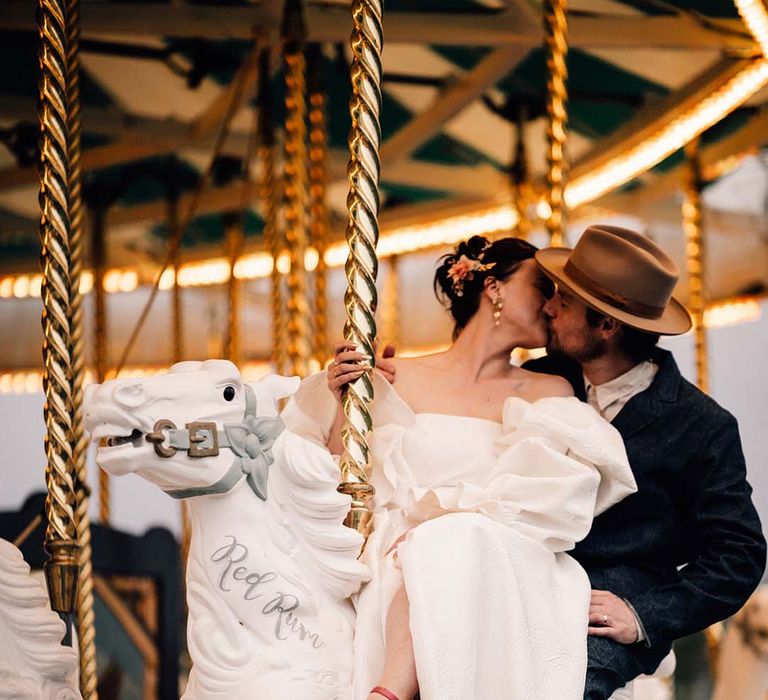 The bride and groom ride on the carousel at Preston Court in Kent 