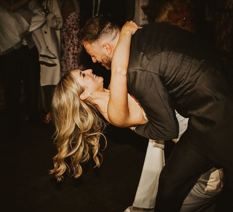 Bride in strapless wedding dress being swept by the groom dancing at the wedding reception 