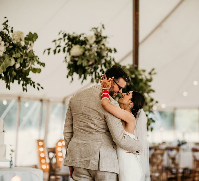 The bride and groom at their classic summer marquee wedding with festoon lights 