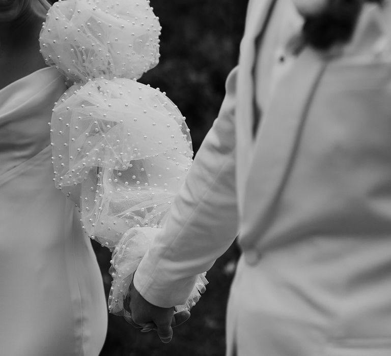 Pearl puff sleeves and Chosen by Kyha wedding dress worn by bride holding hands with the groom 