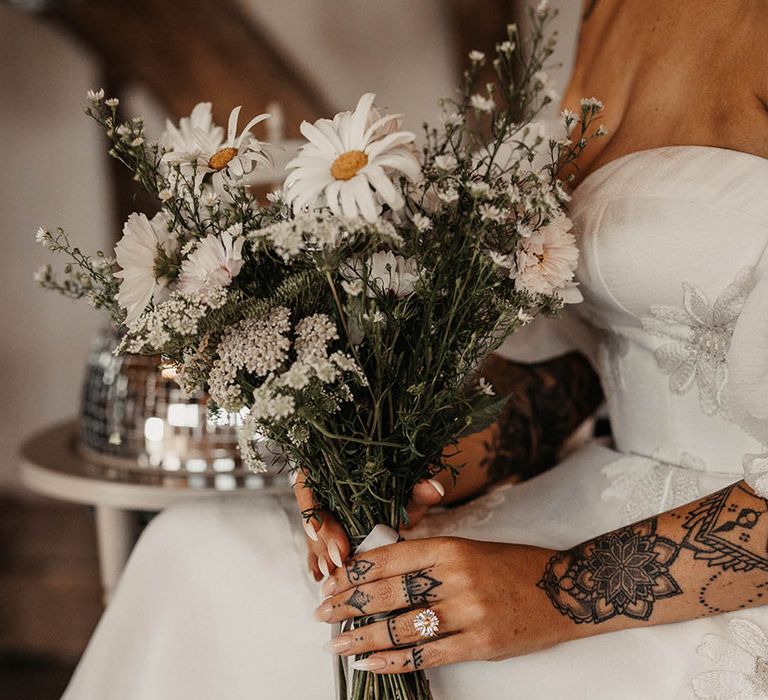 Sustainable wildflower wedding bouquet with daisies held by bride 