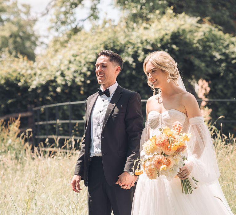 Bride and groom photograph walking in a field