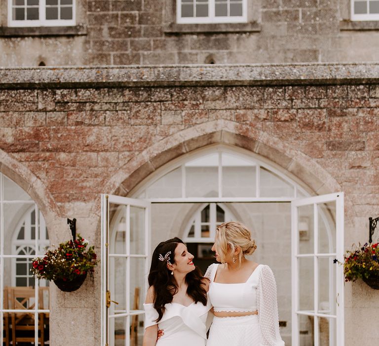 Brides carrying pastel wedding bouquet with wildflowers with one bride in an off the shoulder gown and another in bridal separates 