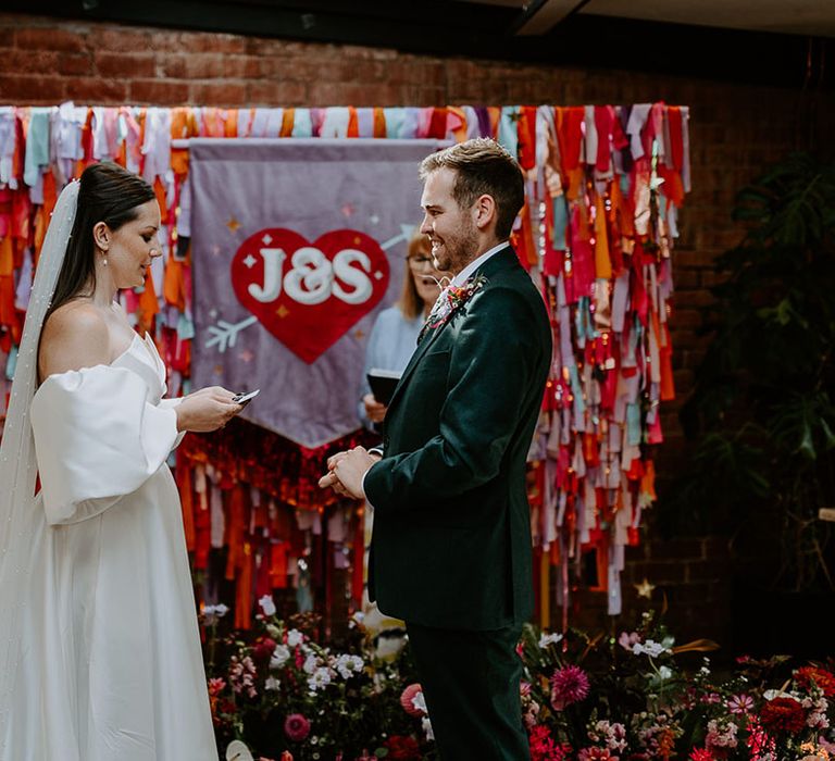 Colourful rainbow streamers DIY wedding altar decoration for 80s theme wedding with the bride and groom for their wedding ceremony 