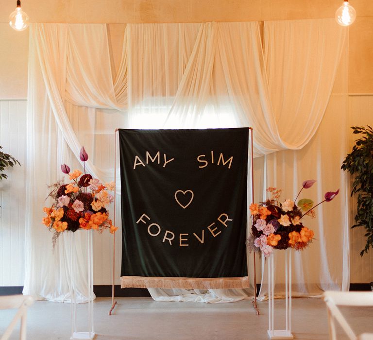 DIY black and white wedding banner sign with white drapery and pastel flowers altar decorations 