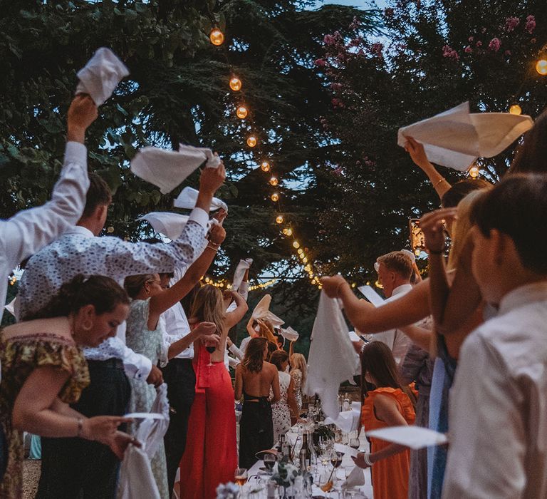 Wedding guests waving their napkins to celebrate the entrance of the bride and groom to the wedding reception 