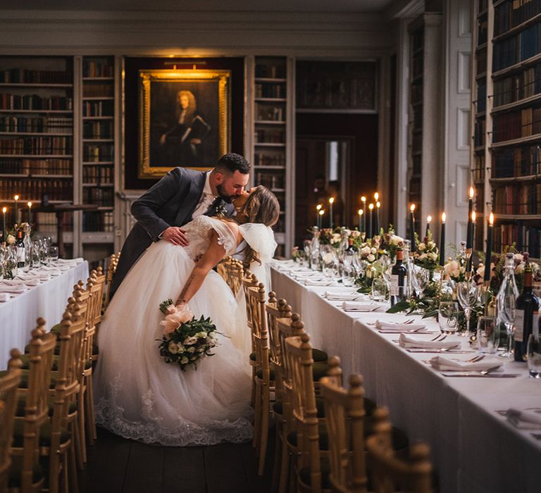 Bride in princess wedding dress kissing the groom at their library wedding breakfast 