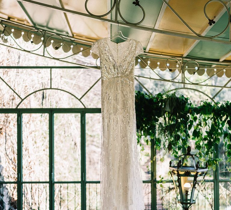 Bride's sequin wedding dress hanging up at castle wedding venue 