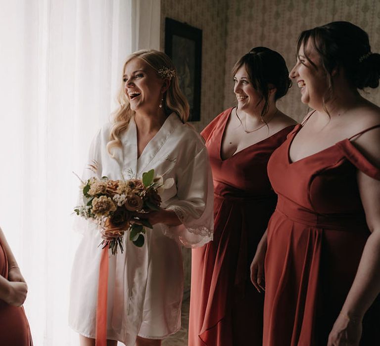 Bridal party in terracotta bridesmaid dresses with the bride in a white robe 