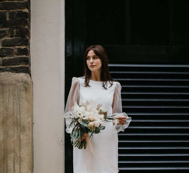 Micro wedding dress by Story Of My Dress with sheer long sleeves and frill edges