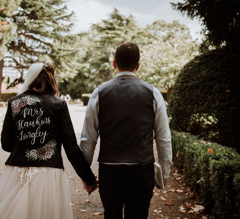 Bride and groom portrait holding hands with bride in a personalised leather jacket 