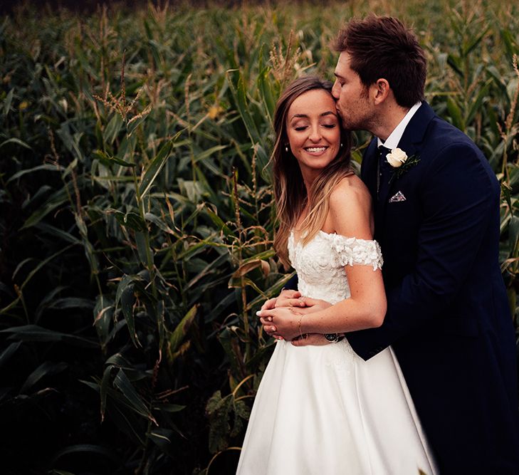 Groom kissing his new bride at country wedding with cold shoulder wedding dress